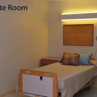 A private hospital room with a single bed and simple decor.