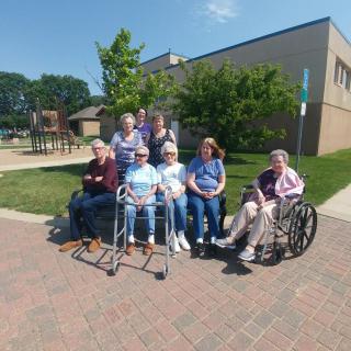 A group of seniors enjoying a sunny day outdoors near a building.