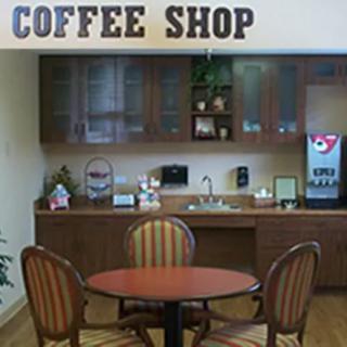 A cozy indoor coffee shop with a small round table and chairs, featuring a beverage machine and cabinets.