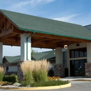 A building entrance with a green roof and landscaping under a clear sky.
