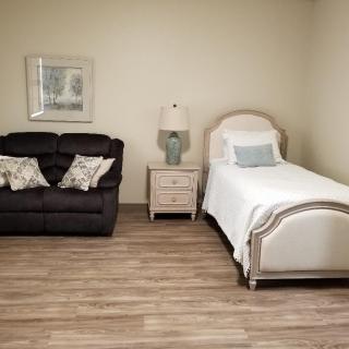 A cozy bedroom with a single bed, a sofa, and minimalistic decor.