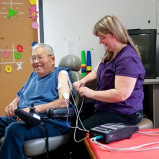 A nurse assists an elderly person with blood pressure monitoring.