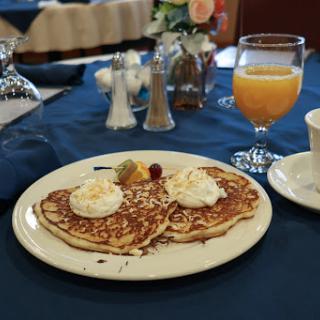 A delicious breakfast featuring heart-shaped pancakes topped with whipped cream, alongside a glass of fresh orange juice.