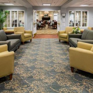A spacious lobby seating area with comfortable chairs and couches, featuring a decorative carpet and welcoming entrance.