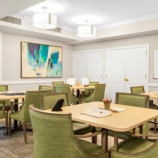 A modern dining area with green upholstered chairs and contemporary artwork.