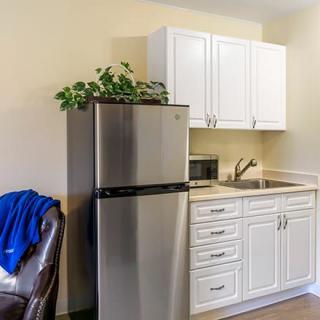 A small kitchen area featuring a refrigerator, white cabinets, and a sink.