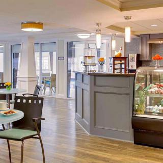 A modern cafe interior with ample seating and a display case of desserts.