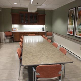 A well-lit conference room with a long table and multiple chairs, suitable for meetings.
