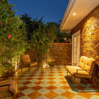A cozy patio area illuminated at night with comfortable seating, surrounded by potted plants and a brick wall.
