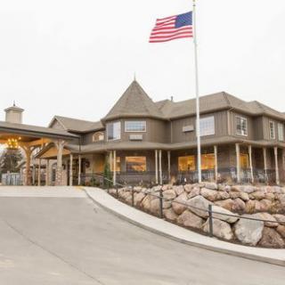 A view of a building with an American flag flying outside, featuring a driveway leading to the entrance.