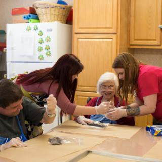 A group of individuals engaged in a fun cooking activity together in a cozy kitchen.