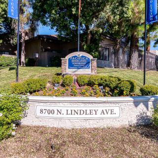 Image of an apartment complex entrance with signage and landscaping at 8700 N. Lindley Ave.