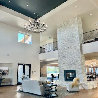 A spacious and elegantly designed living room featuring a modern chandelier and a stone fireplace, perfect for cozy gatherings.