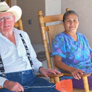 An elderly couple sitting together on rocking chairs.