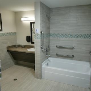 A modern and accessible bathroom featuring a bathtub and sink, designed for convenience and style.
