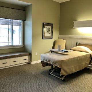 A well-lit hospital room featuring a single bed, a window with a view, and minimalist decor.