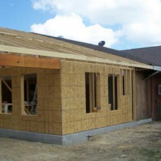 A partially constructed house with wooden framing and visible open spaces for windows.