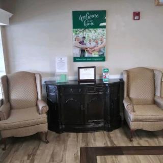 A waiting room with two armchairs and a sideboard, featuring a welcoming poster on the wall.