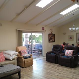 A cozy living room with recliners and couches, featuring skylights and a sliding door leading to an outdoor balcony.