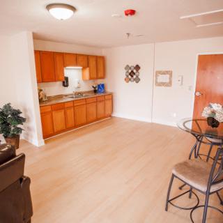 A modern kitchen and dining area featuring wooden cabinets, a small table, and cozy seating.