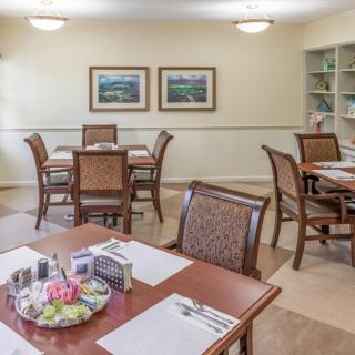 A cozy dining area with tables and chairs, decorated with framed artwork on the walls.