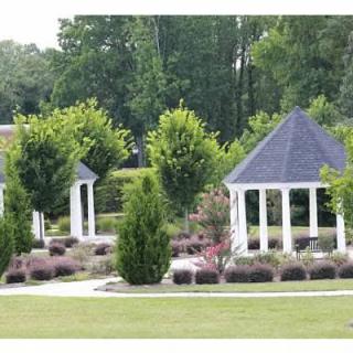 Two white gazebos surrounded by lush greenery and pathways in a landscaped garden.