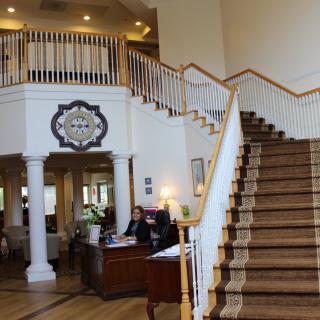 A spacious lobby with a grand staircase and a reception desk.
