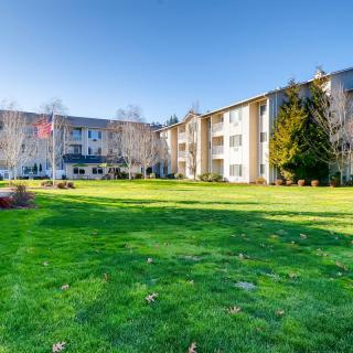 A residential apartment building complex with a well-maintained green lawn under a clear blue sky.