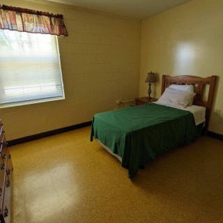 A simple bedroom with a single bed and wooden furniture.