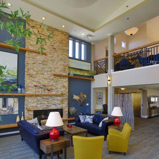 A spacious and modern living room with a stone fireplace, colorful decor, and loft area.
