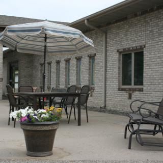 A cozy outdoor patio featuring a table with an umbrella, surrounded by chairs and a flower pot.