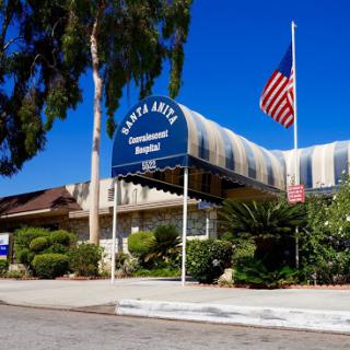Santa Lisa Hospital with a clear blue sky and an American flag in the foreground.