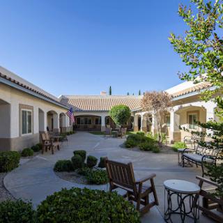 A serene courtyard featuring outdoor seating and well-maintained landscaping under a clear blue sky.