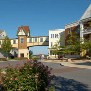 A picturesque view of a pedestrian bridge connecting buildings surrounded by landscaping and trees.