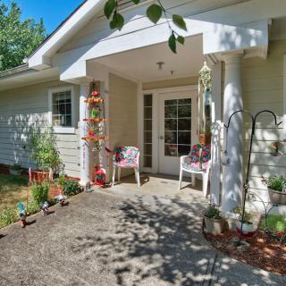 A cozy front porch with seating and decorative plants on a sunny day.