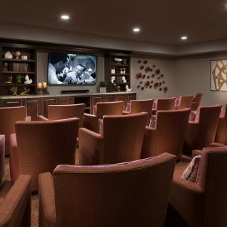 A cozy home theater with comfortable seating arranged in rows facing a large screen.