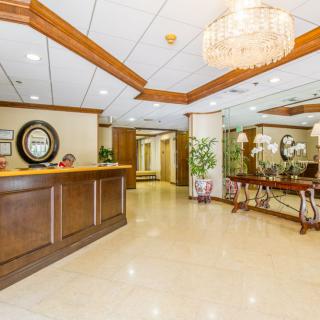 A spacious lobby area with a wooden reception desk, decorative mirrors, and elegant lighting.
