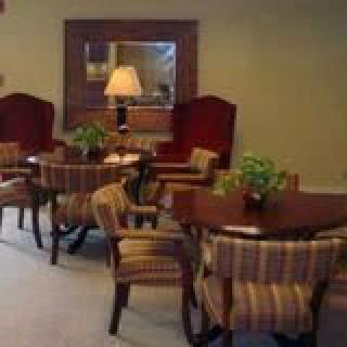A cozy seating area with tables, chairs, and a lamp.