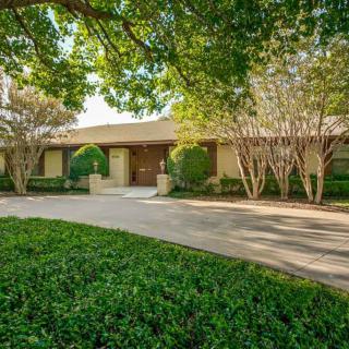 A suburban house surrounded by trees and greenery with a spacious driveway.
