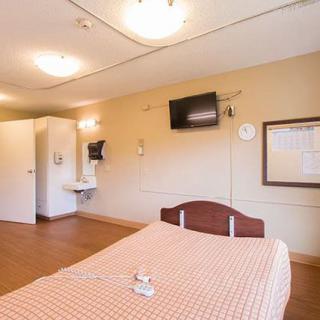 A clean, well-lit hospital room with a single bed and a wall-mounted television.