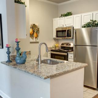 A modern kitchen featuring granite countertops and stainless steel appliances, accented with decorative candles.