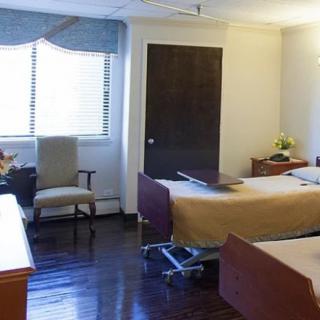 A hospital room with two patient beds and wooden flooring.