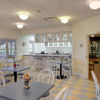 A cozy and well-lit cafe dining area with several tables and chairs.