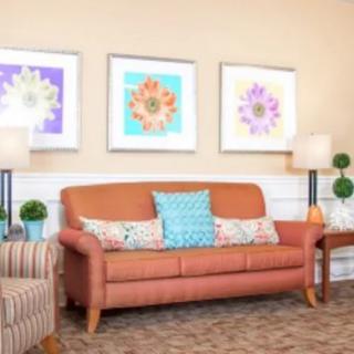 A cozy living room featuring a leather sofa adorned with colorful cushions, accompanied by elegant artwork and decorative lamps.