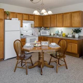 A cozy kitchen with wooden cabinets, a round dining table, and essential appliances.