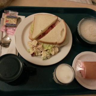 A meal tray with a sandwich, salad, and beverages.