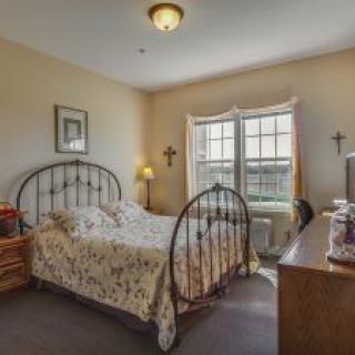 A cozy bedroom with a metal bed frame, floral bedding, and warm lighting.