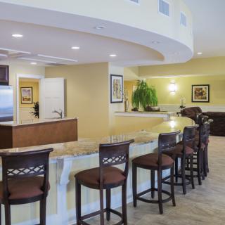A modern kitchen and bar area with high stools and a curved countertop.
