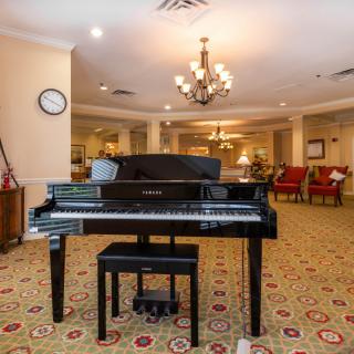 A grand piano in a warmly decorated living room with a chandelier.