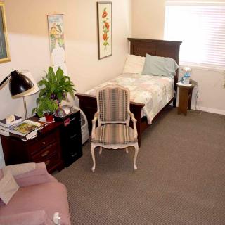 A cozy bedroom with a single bed, wooden furniture, and decorative items.